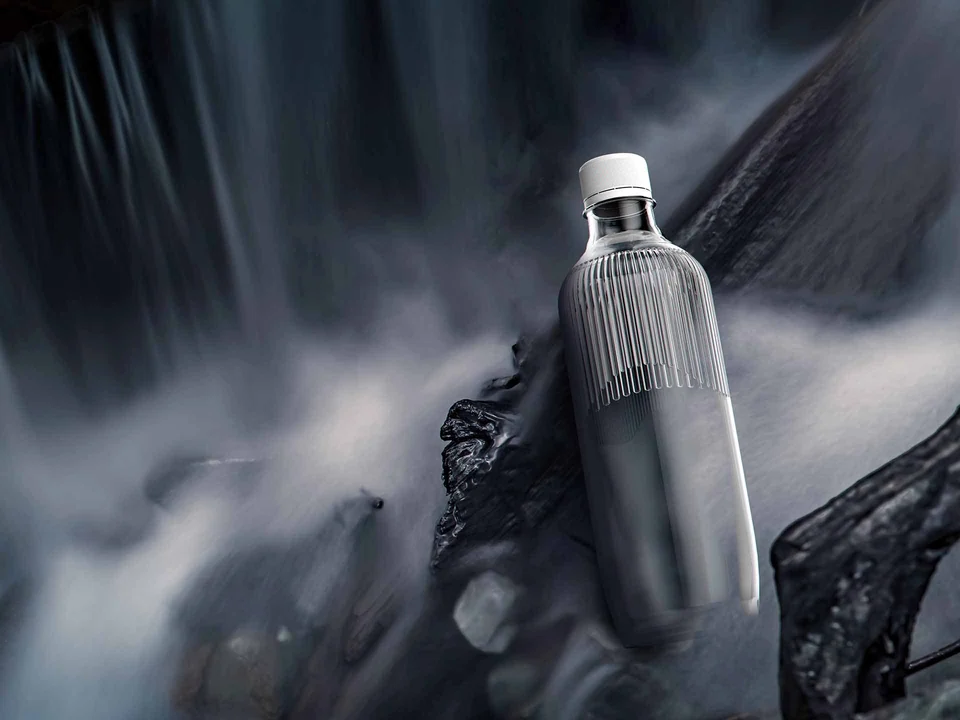 Ribbed Heavenly Curtain bottle resting on dark rocks beside flowing water